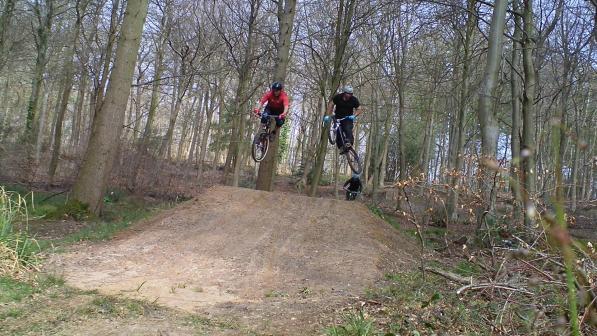 Riders from Bike Park Bishopstoke jumping over a dirt jump