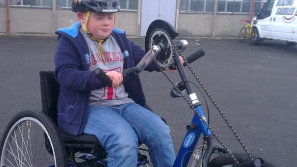 A young boy riding a hand trike