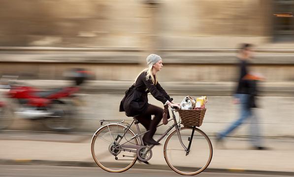 Woman cycling with shopping in her basket