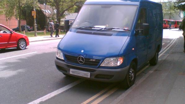 Van parked in mandatory cycle lane with double yellow line.