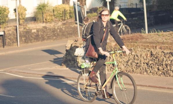 Woman cycles with shopping in a basket on back of her bike