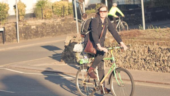 Woman cycles with shopping in a basket on back of her bike