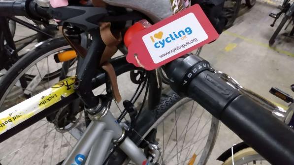 A bike leaned against railings at the beach with a small dog sat on the floor and a child buggy behind the bike