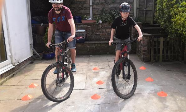 A man and his son practice on bicycles in a small patio area