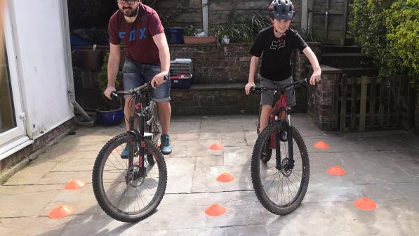 A man and his son practice on bicycles in a small patio area