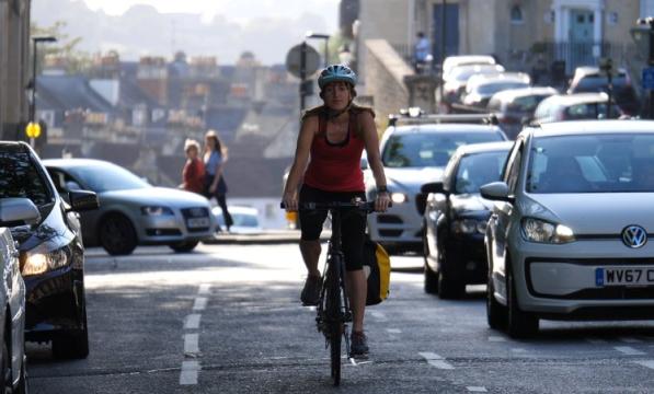 Woman cycles alongside traffic