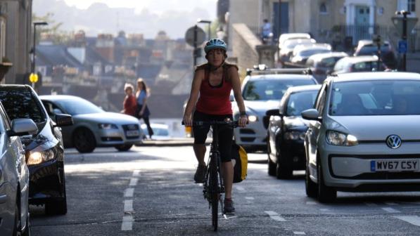 Woman cycles alongside traffic