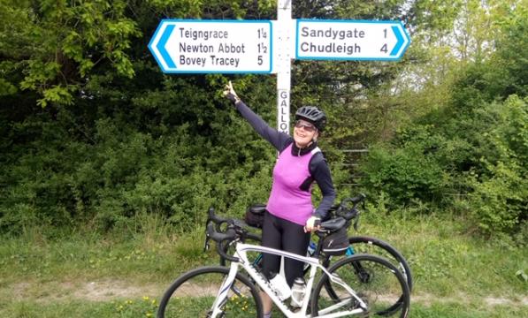 Cyclist pointing at a road sign. Photo by South Devon CTC