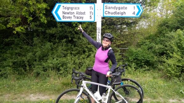 Cyclist pointing at a road sign. Photo by South Devon CTC