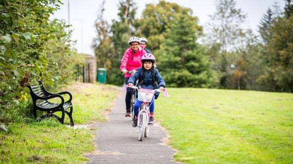 A family with young daughter cycling in the park