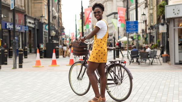Woman standing next to a bike in a high street