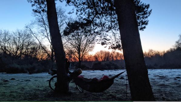 A bikepacker on a frosty morning in their hammock