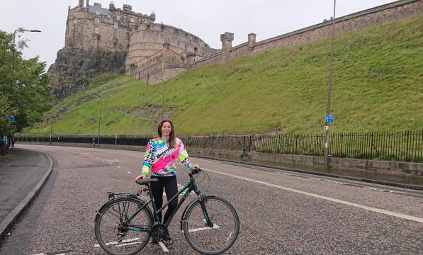 Woman with bike standing on road under Edinburgh Castle
