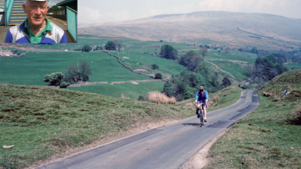 A vintage colour photograph of a man wearing blue cycling in a scenic landscape 