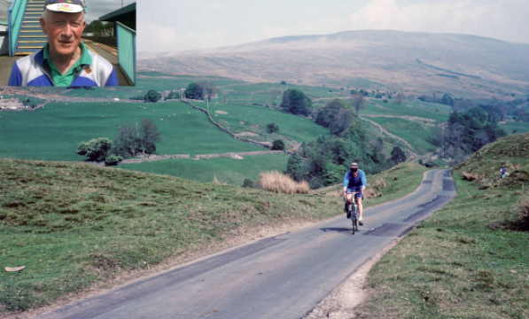 A vintage colour photograph of a man wearing blue cycling in a scenic landscape 