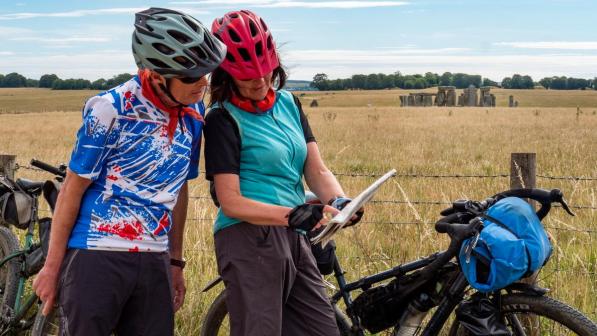 A woman and man looking at a map in front of Stonehenge