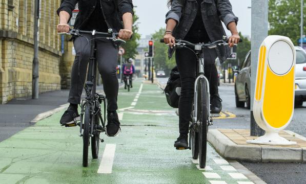 Two people cycling along a cycle lane 
