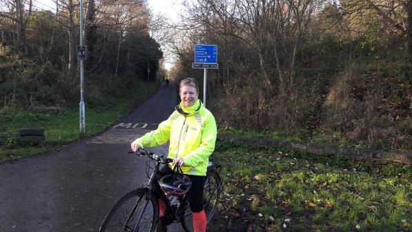 woman with bike on cycle path standing in front of signpost