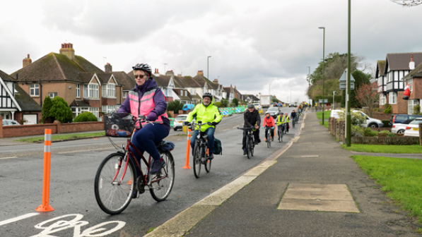 A group of cyclists riding alongside the kerbside in a residential area