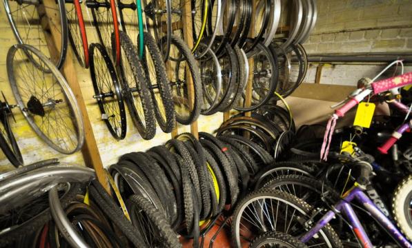 A row of bike wheels in a storage space in a workshop with yellow walls