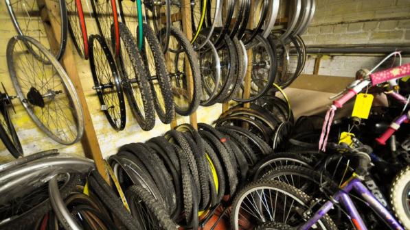 A row of bike wheels in a storage space in a workshop with yellow walls