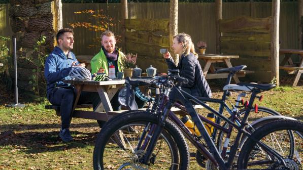Three cyclists at an outdoor cafe discussing cycling  