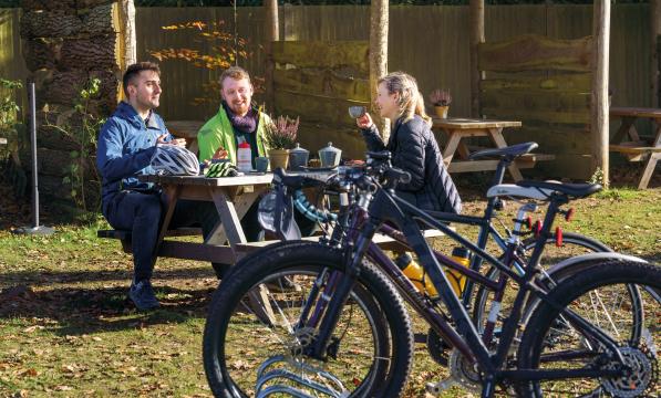 Three cyclists at an outdoor cafe discussing cycling  