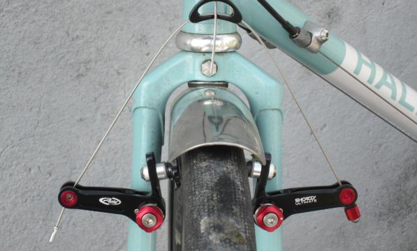 The red and black front cantilever brake in situ on a pale turquoise bike