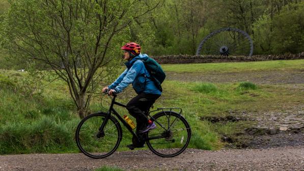 Person cycling past a large memorial wheel in the background
