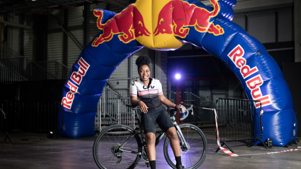 Woman leaning on a road bike while standing in front of a Red Bull branded arch