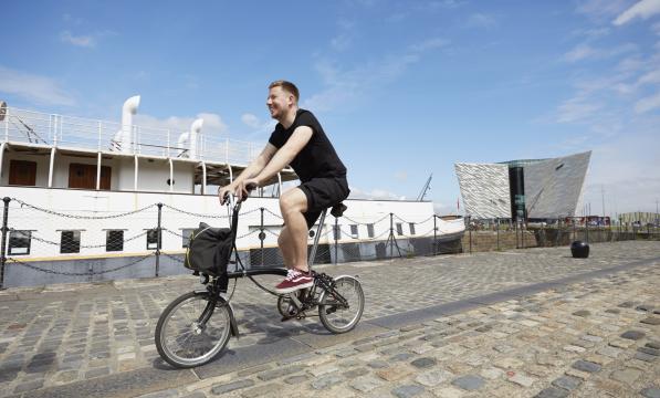 A man cycles along a cobbled harbour