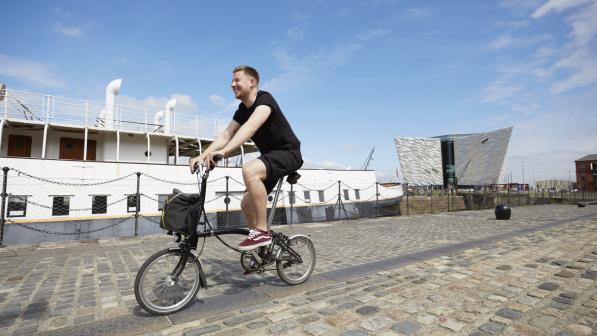 A man cycles along a cobbled harbour