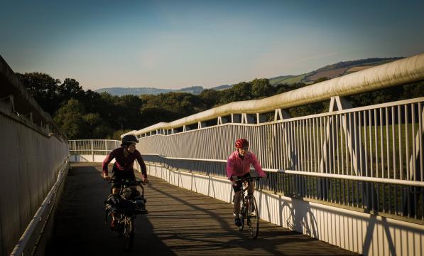 two women cycling over a bridge
