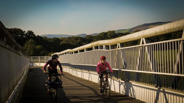 two women cycling over a bridge