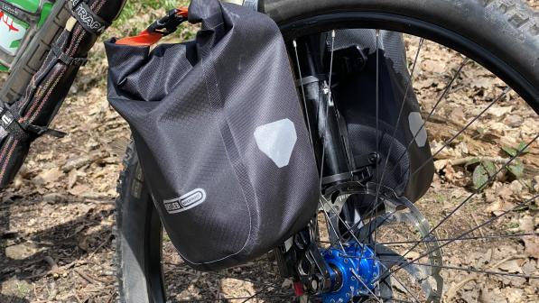 A close-up of a packed Ortlieb Fork Pack attached to a mountain bike front fork