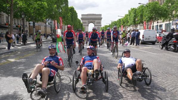 three men side by side on recumbent trikes with Arc de Triomphe in the background