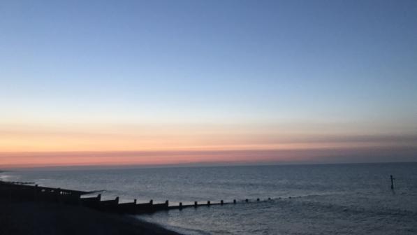Sun setting on the sea, a beach in the foreground