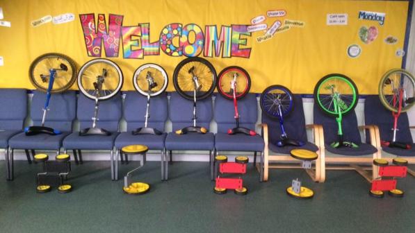 A selection of coloured unicycles, indoors.