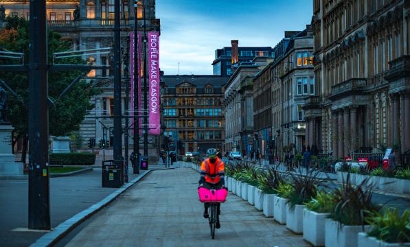 man cycling past planters in George Square, Glasgow