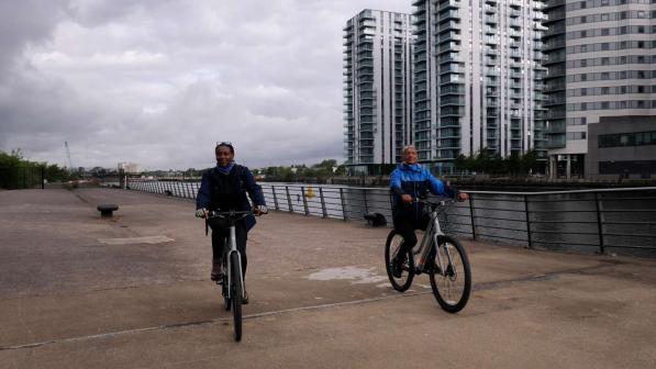 Two people pedalling next to MediaCity in Salford, Manchester prior to the Cycling made e-asy launch