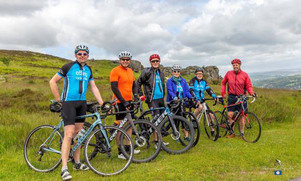 A group of cyclists with their bikes stand on a green hill