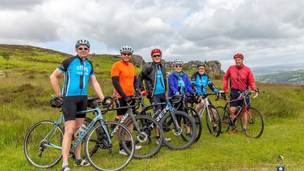 A group of cyclists with their bikes stand on a green hill