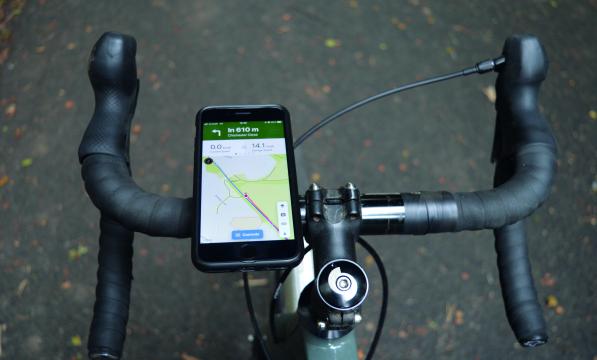 Point of view of a bicycle's handlebars, a phone is mounted to the left hand side, a map showing the route to follow