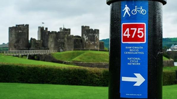 Sign for National Cycle Route 475 with Caerphilly Castle in the background