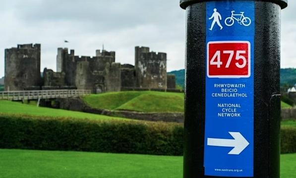 Sign for National Cycle Route 475 with Caerphilly Castle in the background