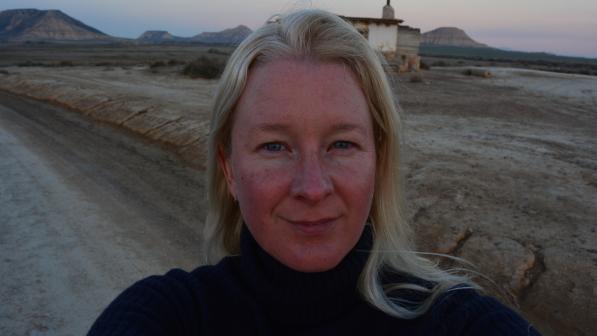Close-up headshot of Anna in a desert landscape. She is wearing a dark jumper. 