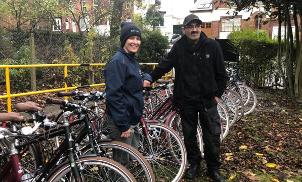 man and woman standing outdoors with a large number of new identical bikes