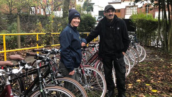 man and woman standing outdoors with a large number of new identical bikes