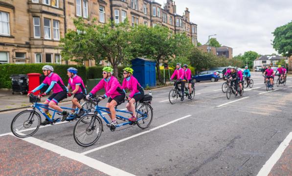 A group of riders on tandems ride along a residential street in Edinburgh