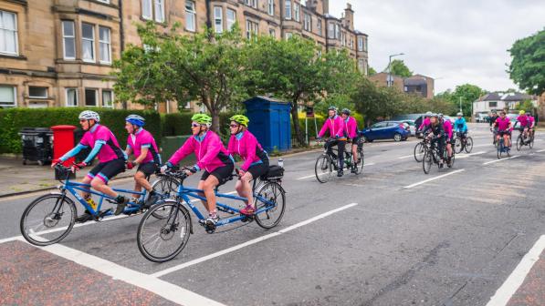 A group of riders on tandems ride along a residential street in Edinburgh